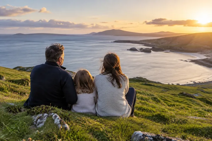 A family looking out over a bay from a grassy headland